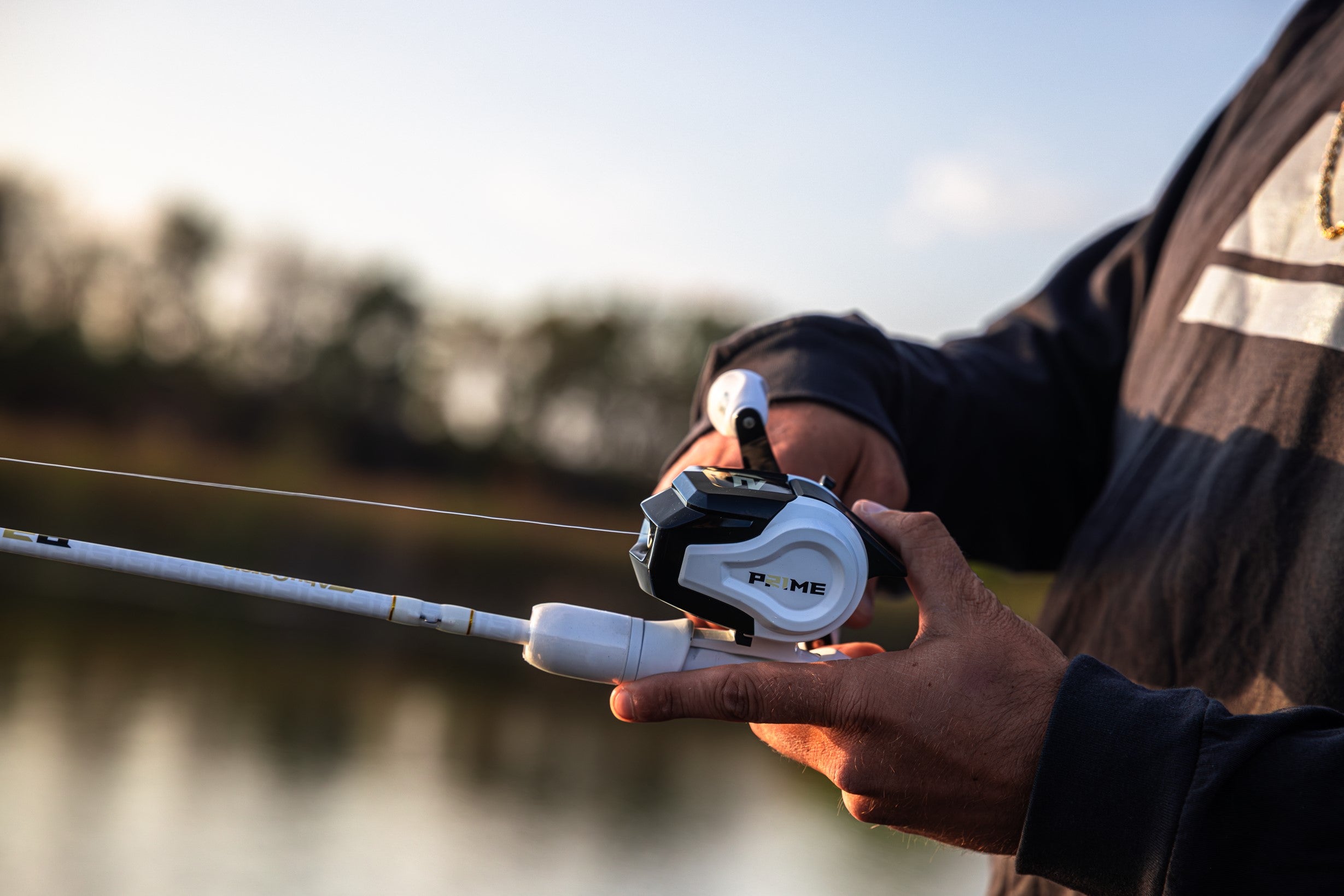 Close up of a Abu Garcia x PRIME21 Spincast Combo in a man's hand over the water 